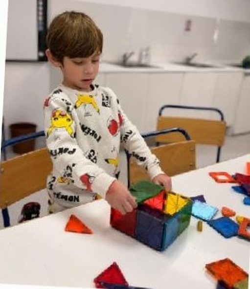 A child building with colourful magnetic tiles