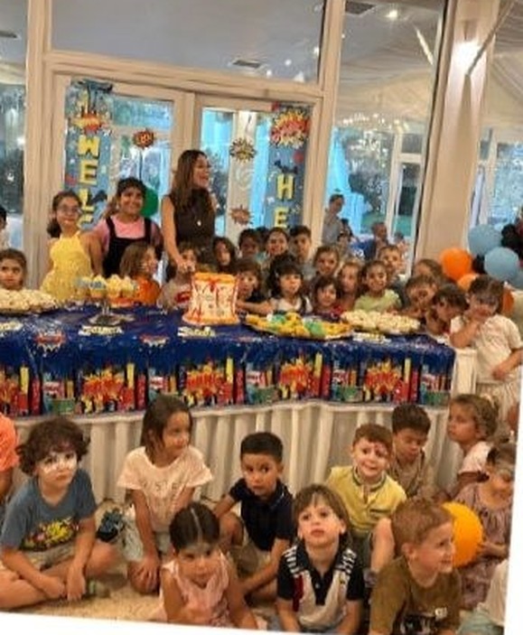 A big group of children around a decorated party table