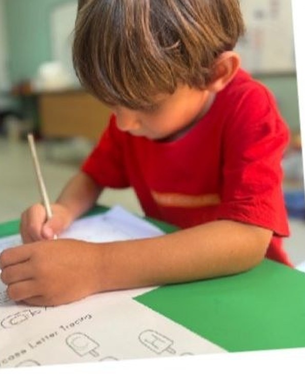 A child concentrating on a drawing at the craft table