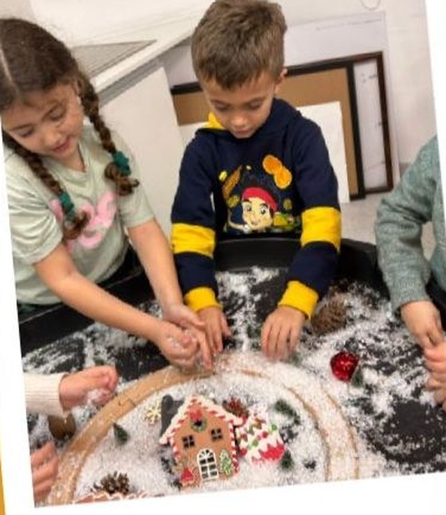 Two children decorating a gingerbread house together