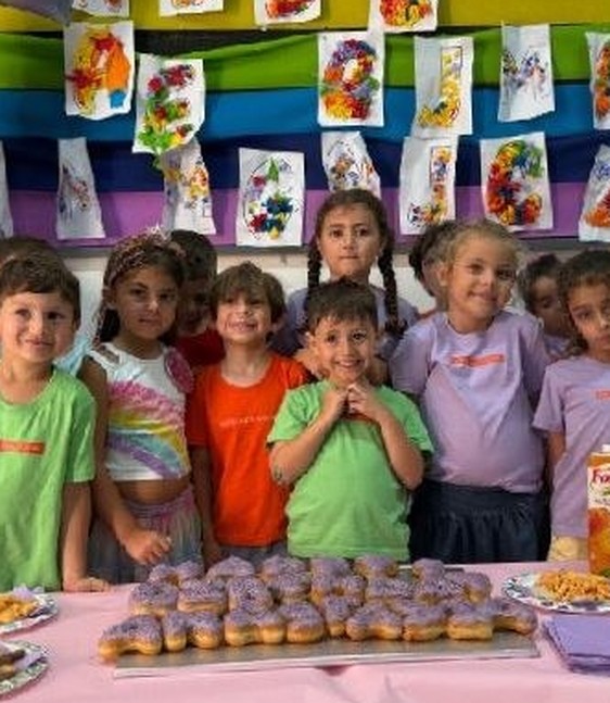 Children in front of a rainbow wall of their own artwork