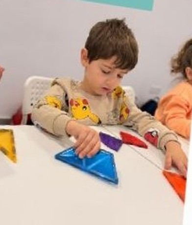 A child sorting bright shapes with a friend nearby