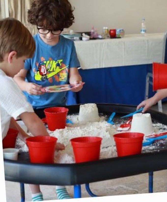Children scooping water and foam at the water table