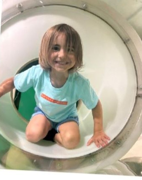 A smiling child crawling through a play tunnel